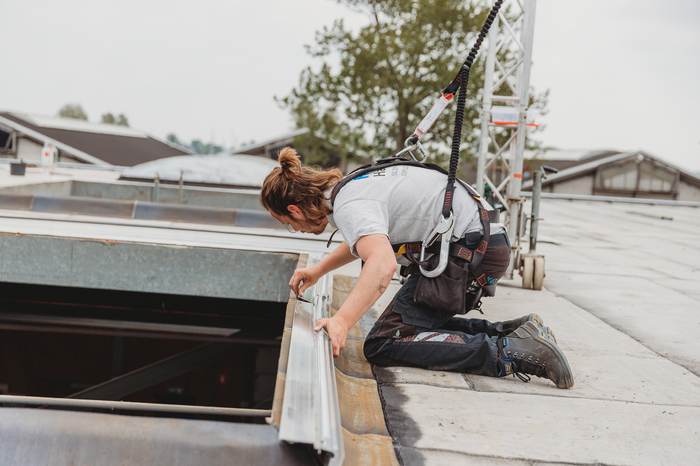 Monteur werkt met veiligheidslijn op hoogte aan een lichtstraat