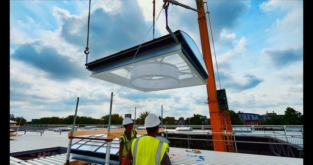 Monteurs en kraan plaatsen geprefabriceerde lichtstraatunit op industrieel dak