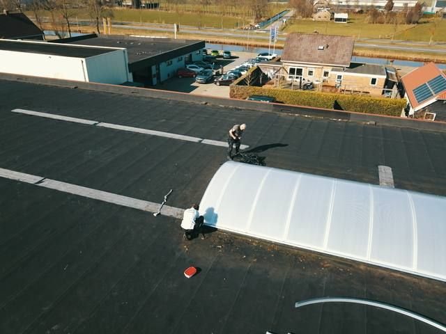 Monteur naast gebogen lichtstraat op plat dak, afwerking bezig, Westerman Nieuwleusen