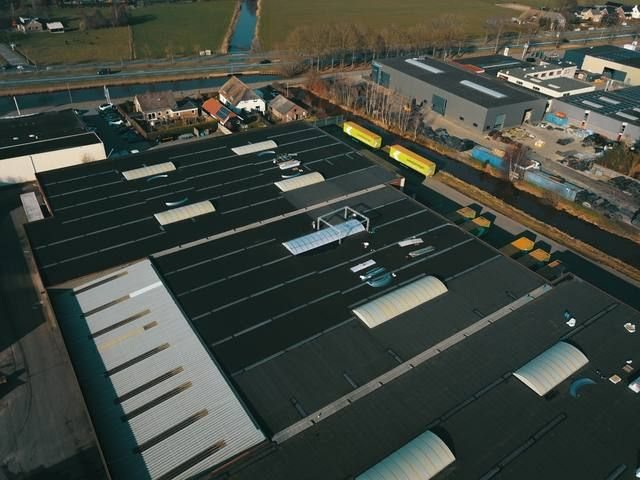 Droneoverzicht bedrijfscomplex Westerman Nieuwleusen met lange rijen lichtstraten op het dak