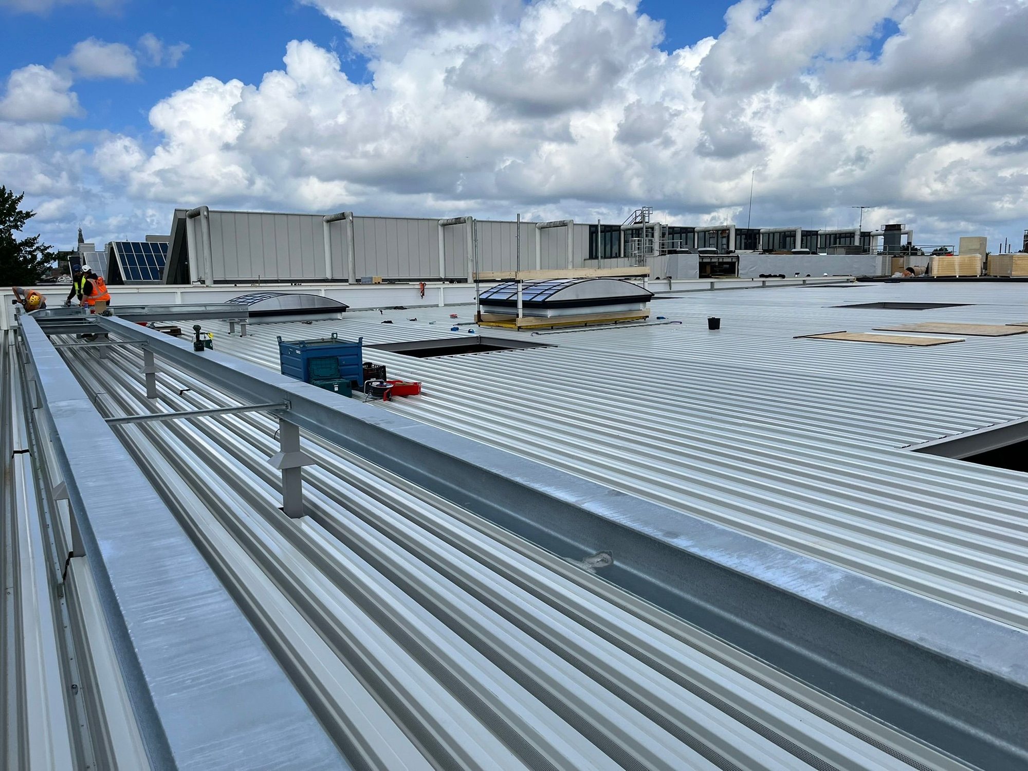 Afgewerkte gebogen lichtstraten in rijen op een metalen dak, NS treinstelhallen