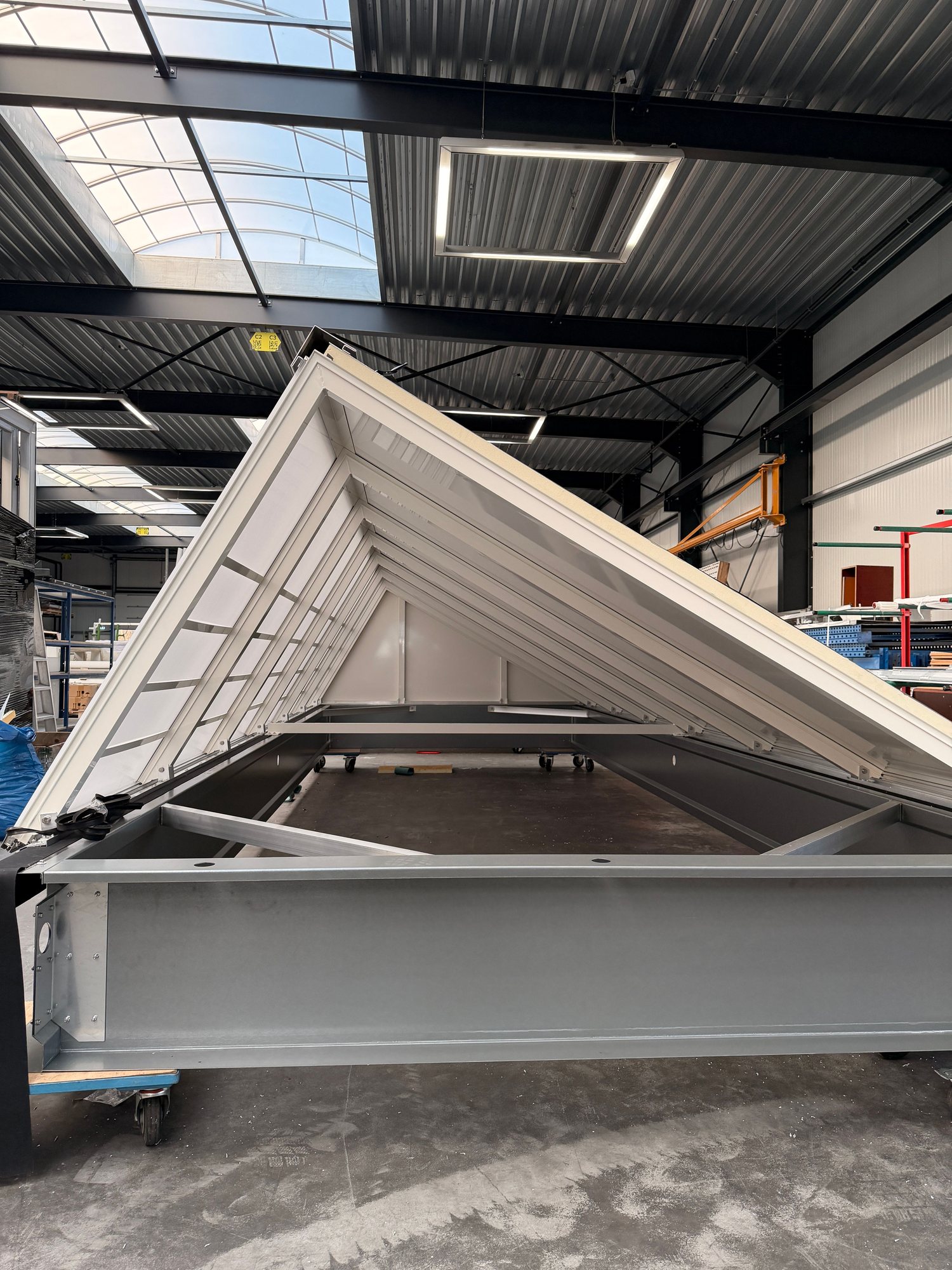 Kopse aanzicht van een prefab zadeldak lichtstraat-element met opengeklapte kap en nokopbouw