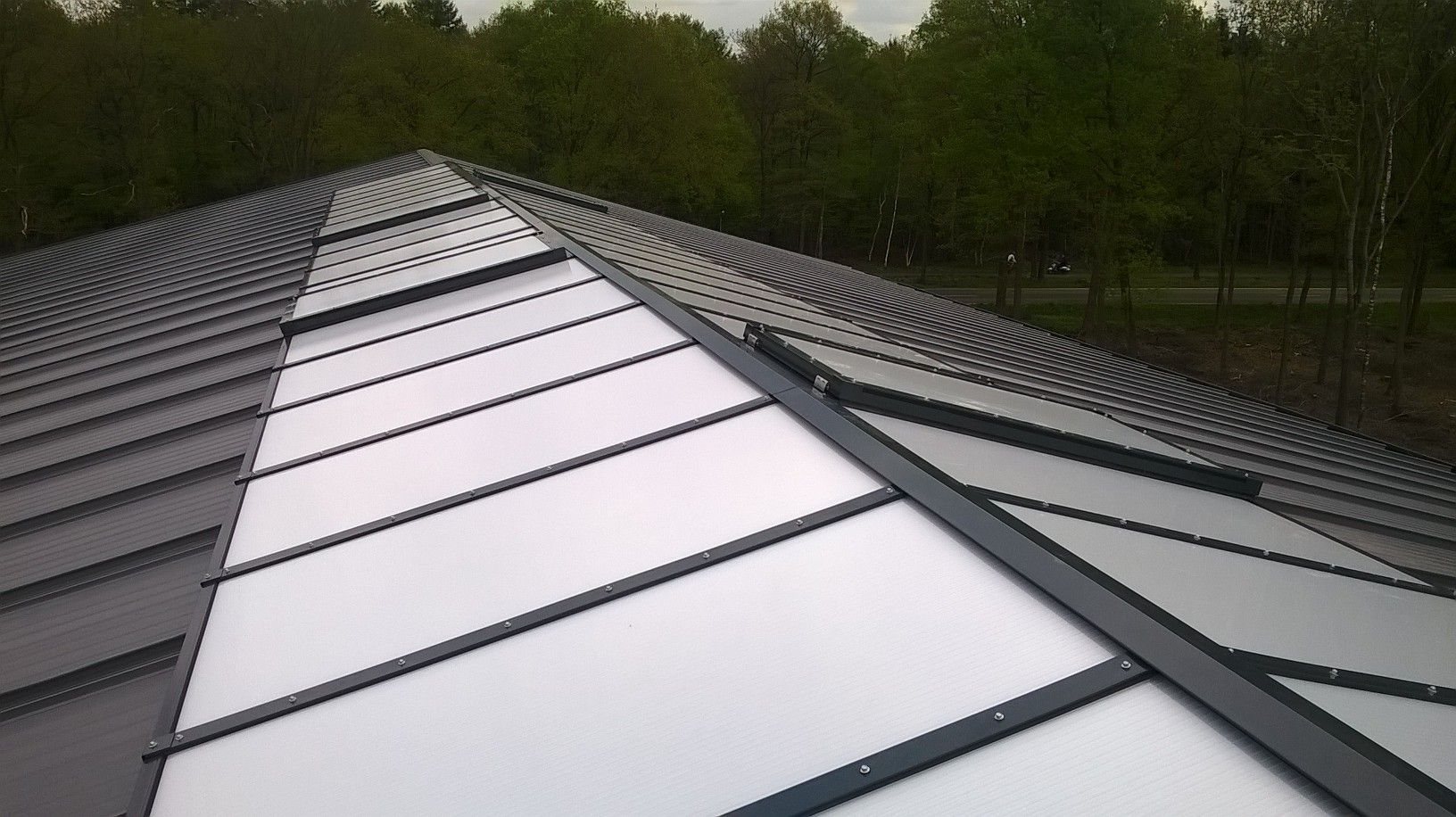 Lange vlakke lichtstraat over de nok van een industrieel dak, symmetrisch perspectief