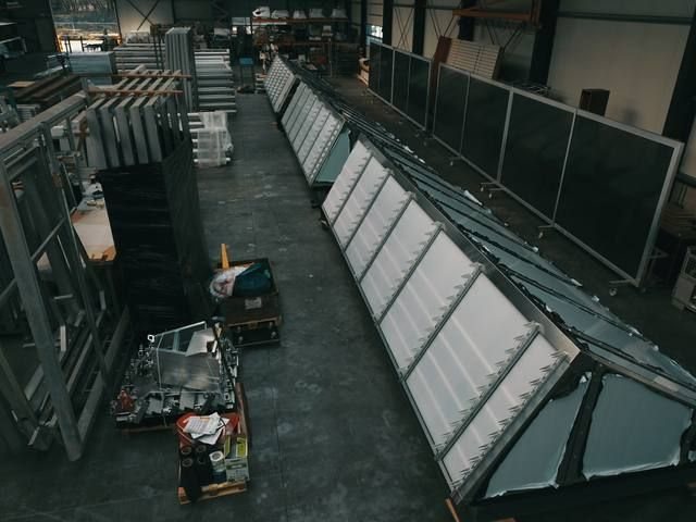 Brede opname van de productiehal met rijen prefab sheddak-elementen en daglicht van bovenaf