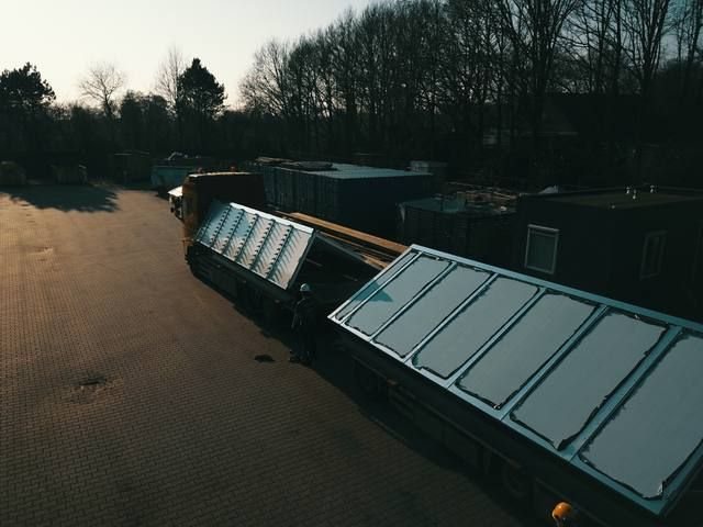 Prefab sheddak-element van dichtbij op de dieplader, glaspanelen glanzen in de zon