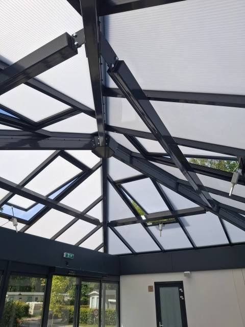 Interieuropname van onderaf door een lichtstraat, staalconstructie en doorschijnende panelen, project Wedderbergen
